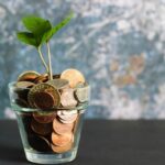 Glass of coins with a small plant inside.