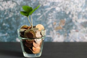 Glass of coins with a small plant inside.